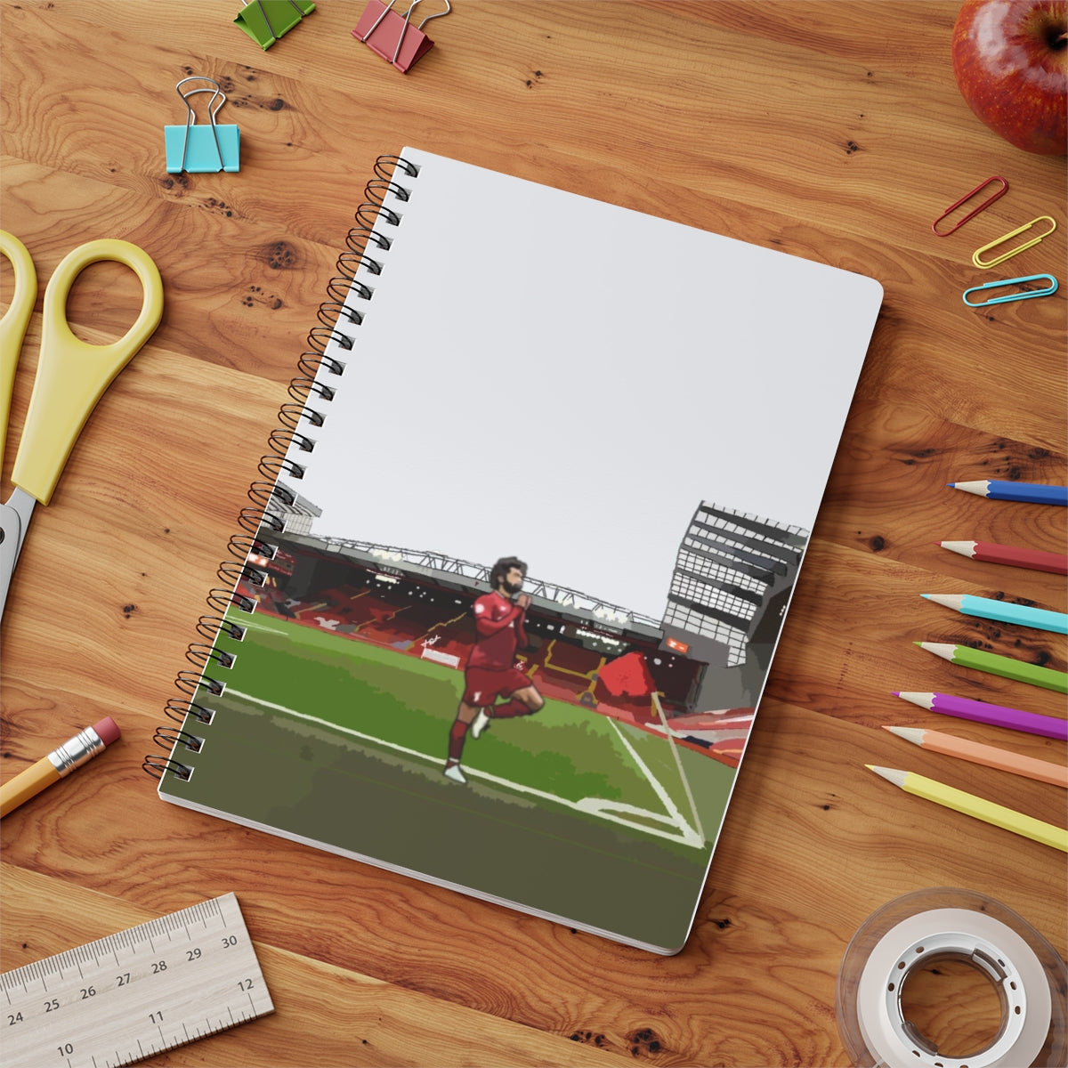 Contextual Front view of Liverpool Mohammed Salah in front of Anfield background on A5 spiral notepad on table top.