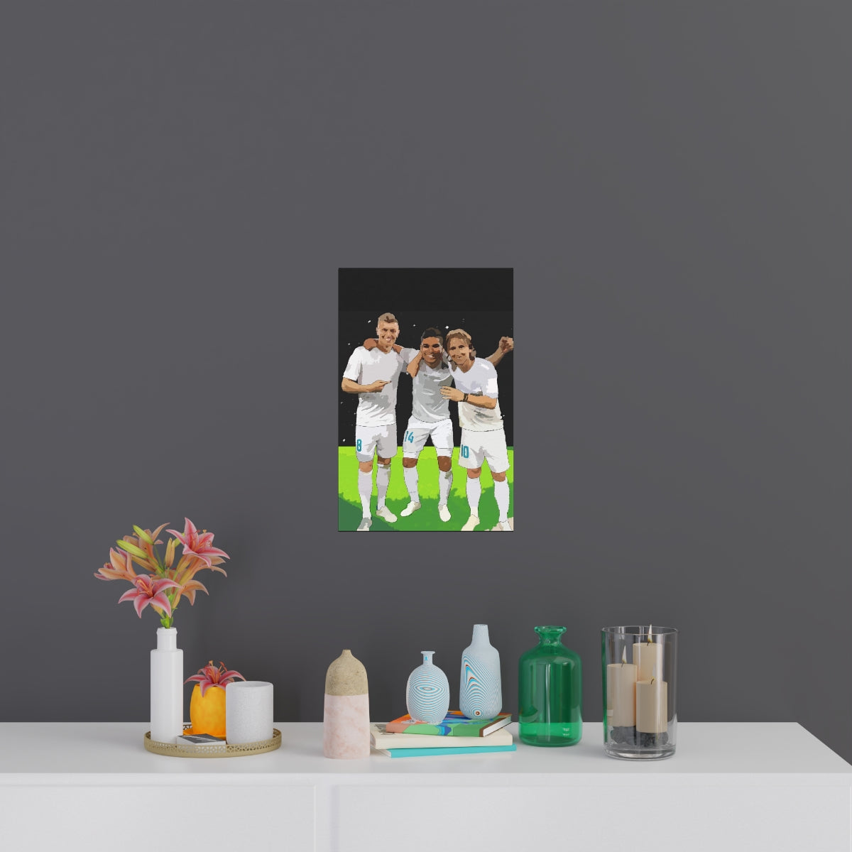 Contextual Front view of Toni Kroos, Casemiro and Luka Modric arm in arm on a black poster hanging on a wall.