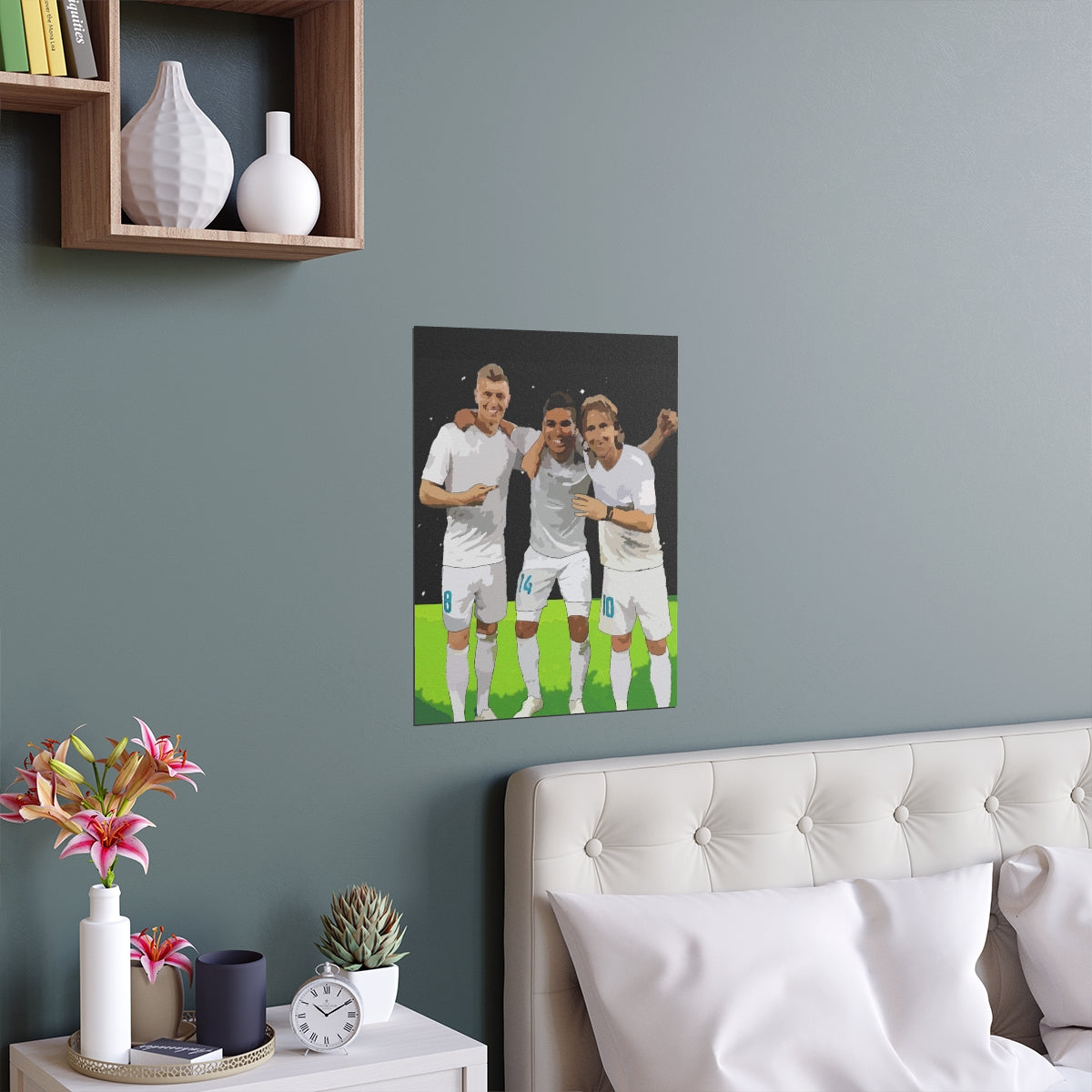 Contextual Front view of Toni Kroos, Casemiro and Luka Modric arm in arm on a black poster hanging on a wall above a double bed.