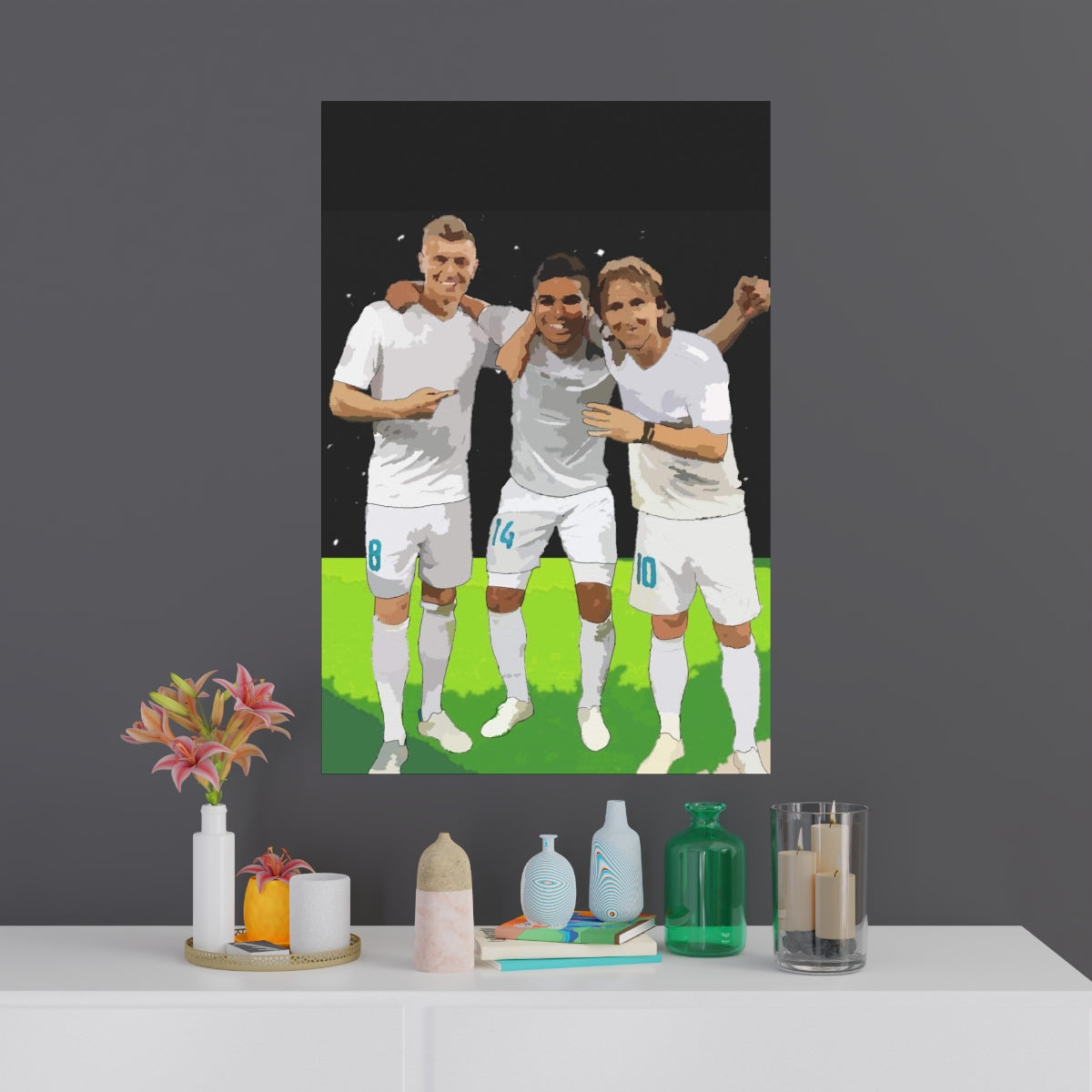 Contextual Front view of Toni Kroos, Casemiro and Luka Modric arm in arm on a black poster hanging on a wall.