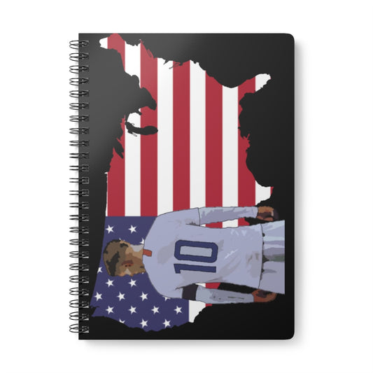 Front view of Christian Pulisic in USMNT kit in front of USA themed background of flag inside country outline black A5 spiral notepad.